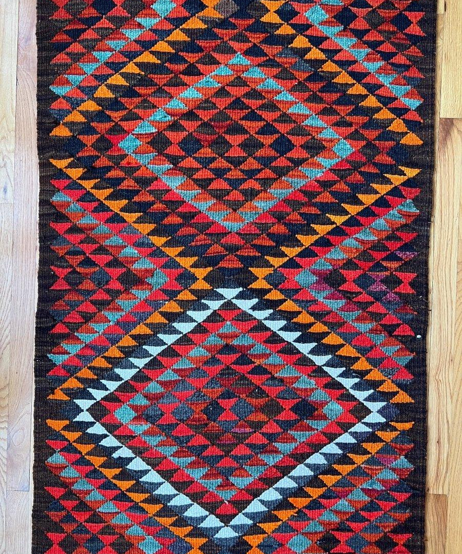Multicolor geometric runner rug with diamond pattern in red, blue, orange, teal, and black
