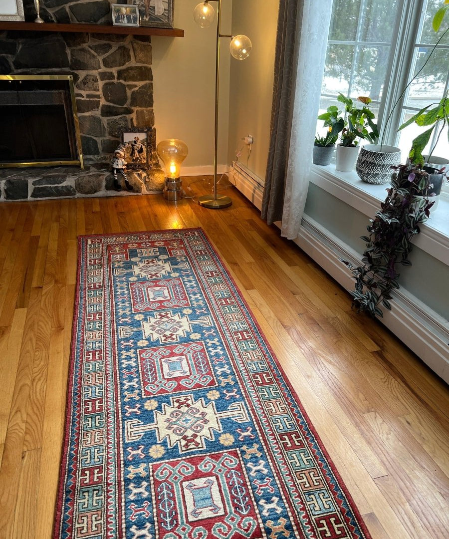 Kazak runner rug on hardwood floor, blue and red medallion geometric design