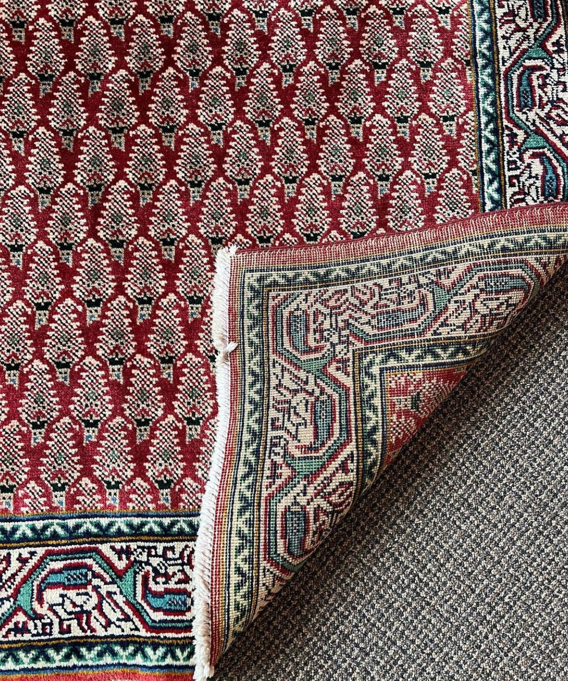 Tabriz rug corner detail, red lattice pattern with navy teal border and folded edge