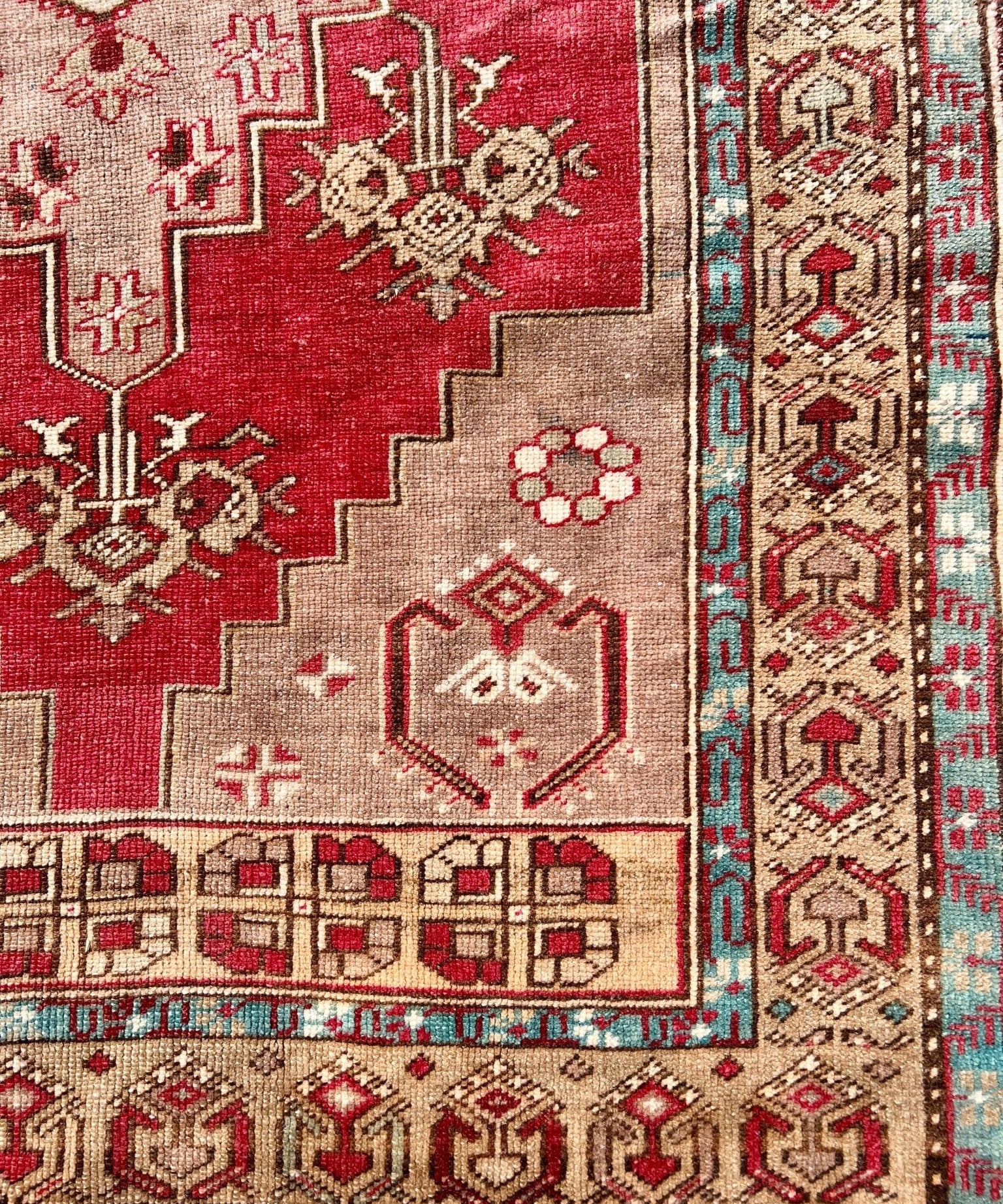 Close-up of red Turkish rug panel with cream and beige geometric motifs and border